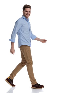 Beyaz stüdyo arka planında yürürken gülen sıradan bir adamın yan görünüşü