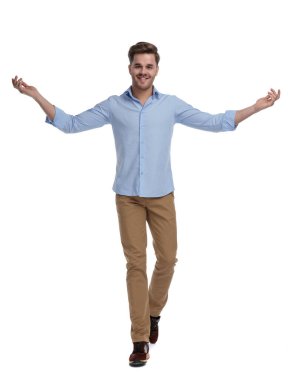 Tişört giyerken gülümseyen ve davetkâr, beyaz stüdyo arka planında yürüyen