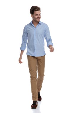 Mutlu sıradan bir adam gülümsüyor ve gömlek giyip beyaz bir stüdyoda homurdanırken başka tarafa bakıyor.