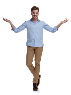 Neşeli sıradan selamlaşma ve davet, tişört giyerken gülümseme ve beyaz stüdyo arka planında durmak.