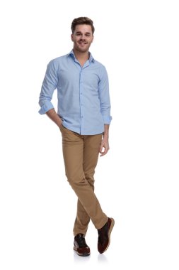 Gömlek giyerken ve beyaz stüdyo arka planında dururken eli cebinde gülümseyen mutlu sıradan bir adam.