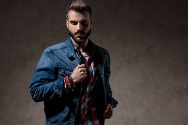 Cesur model, duvar kâğıdı stüdyosunun arka planında dikilirken ceketini sıkıca düzeltiyor.