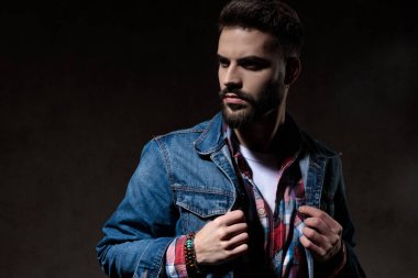 Zor bir model ceketini değiştiriyor, duvar kağıdı stüdyosunun arka planında duruyor.