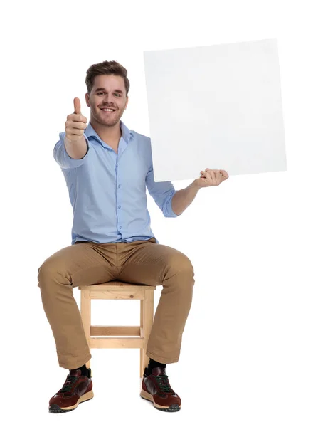 Positivo Casual Homem Segurando Papel Parede Gesto Sorrindo Enquanto Sentado — Fotografia de Stock