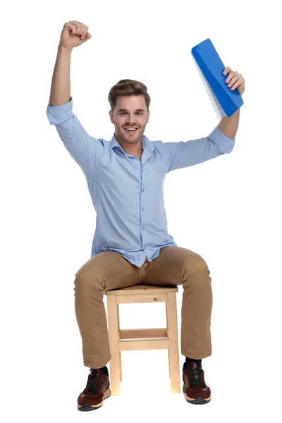 Alegre Hombre Casual Celebrando Con Portapapeles Mano Mientras Está Sentado —  Fotos de Stock