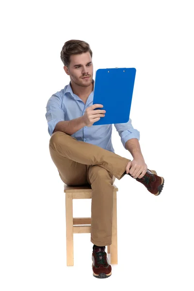 Focused Casual Man Reading Clipboard While Sitting Chair White Studio — Stock Photo, Image