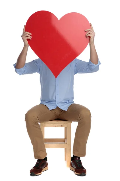 Young Casual Man Covering His Face Heart Shape While Sitting — Stock Photo, Image