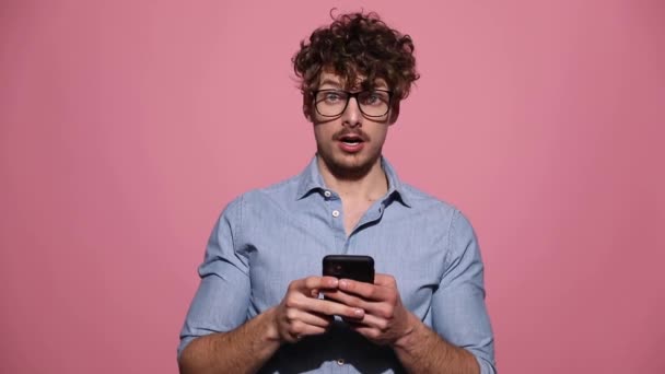 Joven Hombre Casual Con Gafas Pie Lectura Algo Teléfono Sorprendido — Vídeo de stock