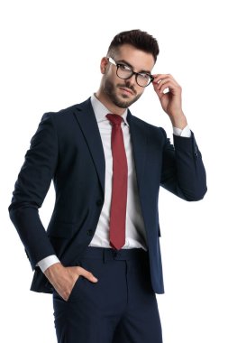 Yakışıklı iş adamı donanma takımı giyiyor. El ele tutuşup beyaz stüdyo arka planında gözlük takıyor.