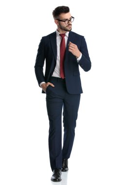 Deniz kuvvetleri kıyafeti giyen seksi iş adamı cebinde ve beyaz stüdyo arka planında havalı bir şekilde yürüyor.