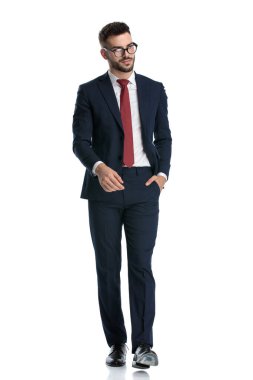 Çekici iş adamı, gözlük takıyor, el ele yürüyor ve beyaz stüdyo arka planında havalı bir tavırla poz veriyor.