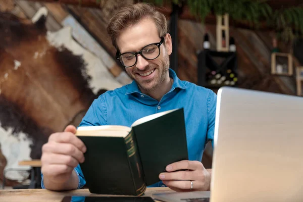喫茶店で幸せ本を勉強して机に座って眼鏡をかけたカジュアルな男 — ストック写真