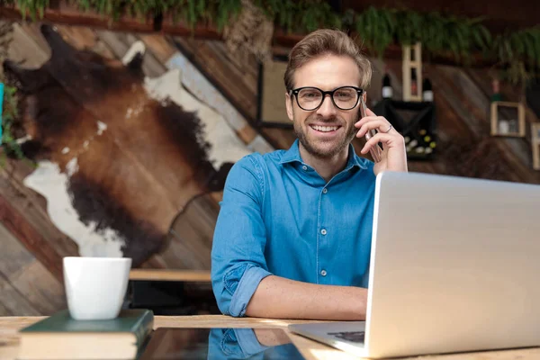 Hombre Casual Con Gafas Sentado Escritorio Hablando Por Teléfono Mientras — Foto de Stock