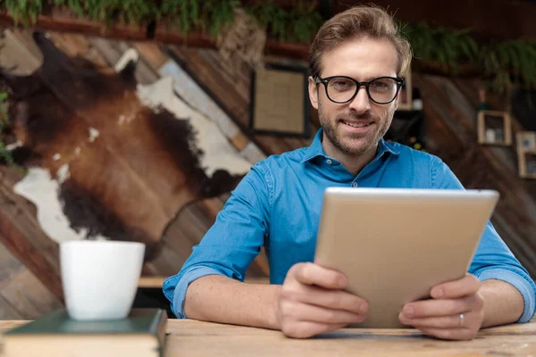 Ležérní Muž Nosí Brýle Sedí Stolem Drží Tablet Zatímco Dívá — Stock fotografie