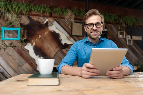 Επιχειρηματίας Φορώντας Γυαλιά Κάθεται Στο Γραφείο Και Κρατώντας Tablet Του — Φωτογραφία Αρχείου