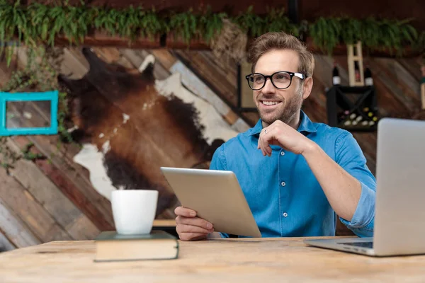 Hombre Casual Con Gafas Sentado Escritorio Trabajando Tableta Mientras Mira —  Fotos de Stock