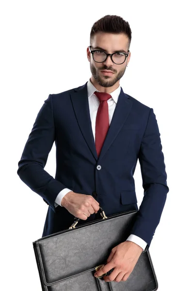 Młody Biznesmen Noszący Okulary Stojąco Trzymający Walizkę Rękach Poważnie Białym — Zdjęcie stockowe