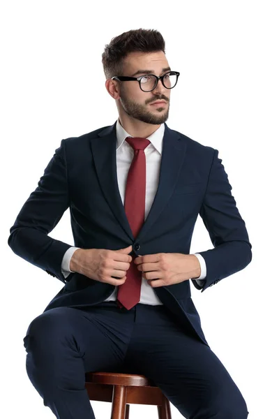 Gözlüklü Çekici Adamı Beyaz Stüdyo Arka Planında Oturuyor Ceketini Açıyor — Stok fotoğraf