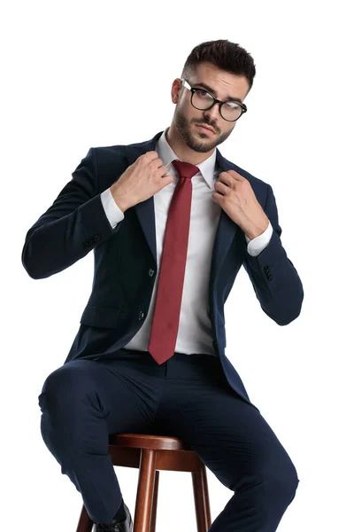 Attraktiver Geschäftsmann Mit Brille Sitzt Und Fixiert Kragen Mit Stil — Stockfoto