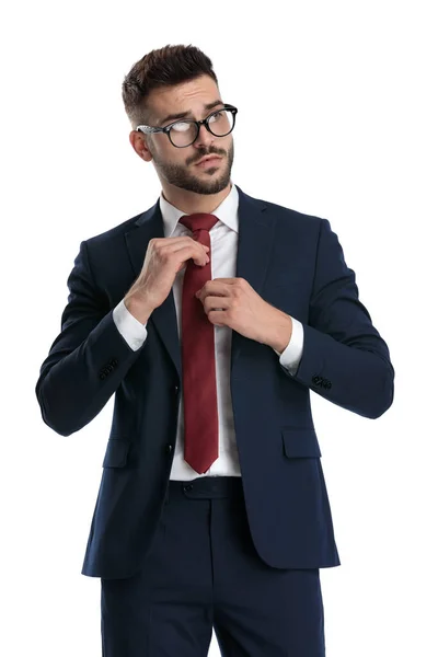 Ελκυστικός Επιχειρηματίας Γυαλιά Στέκεται Και Διορθώνει Γραβάτα Του Στάση Λευκό — Φωτογραφία Αρχείου