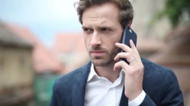 Ciddi bir iş adamını telefonda konuşurken yakalıyor, sonra duvara yaslanıyor ve telefonuna mesaj atıyor.