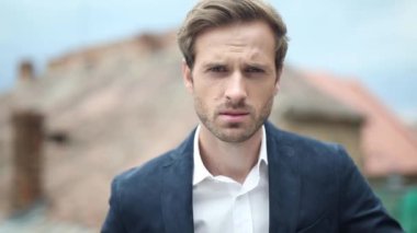 Donanma takımlı havalı bir iş adamının önünde dikilip kameraya bakarken.