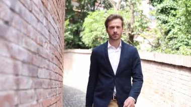 Zeki ve yakışıklı iş adamı yüzünde bir gülümsemeyle yürüyor ve tasmasını dışarıda, tavırlarıyla düzeltiyor.