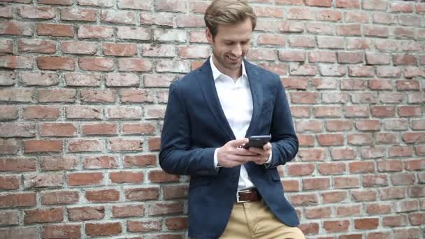 Handsome Young Businessman Wearing Navy Suit Leaning Brick Wall Texting — Stock Video