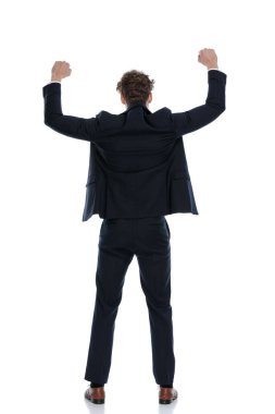 Arka manzara işadamı, takım elbise giyerken ve beyaz stüdyo arka planında dururken yumruklarını havaya kaldırarak kutlama yapıyor.