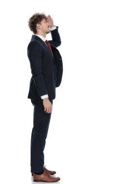 Takım elbise giyerken ve beyaz stüdyo arka planında dururken el ele tutuşan hevesli iş adamının yan görünüşü