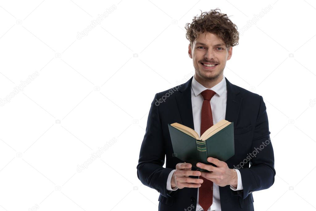 Happy businessman holding book and smiling wearing suit and standing on white studio background