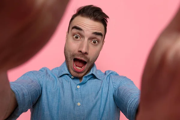 若いセクシーなカジュアル男を保持カメラと作ります面白いと驚きの顔上のピンクのスタジオの背景 — ストック写真