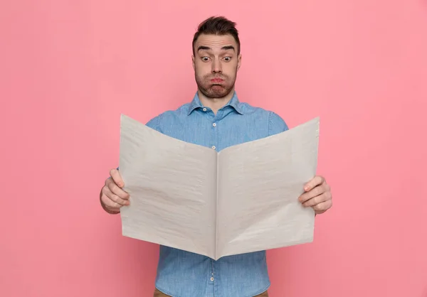 Junger Überraschter Lässiger Mann Liest Zeitung Und Bläst Seine Wangen — Stockfoto