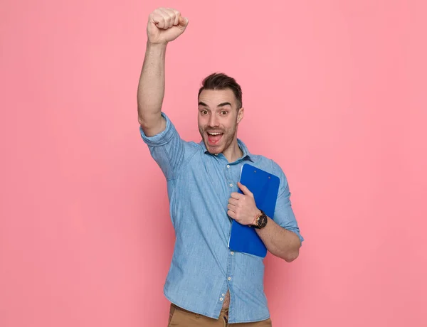 Giovane Uomo Casuale Eccitato Alzando Pugno Aria Tenendo Gli Appunti — Foto Stock