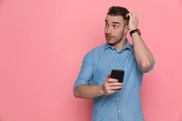 Pohledný Nejistý Ležérní Muž Škrábající Hlavě Dívá Stranou Drží Telefon — Stock fotografie