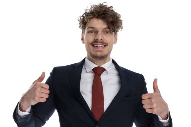 Pozitif iş adamı, takım elbise giyerken ve beyaz stüdyo arka planında dururken iki eliyle gülüyor ve el kol hareketi yapıyor.