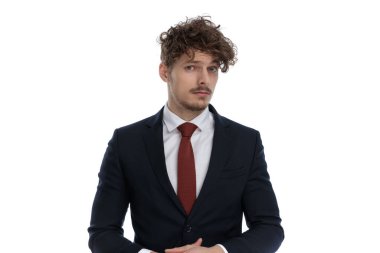 Odaklanmış işadamı takım elbise giyerken ve beyaz stüdyo arka planında dururken aynı fikirde değil.