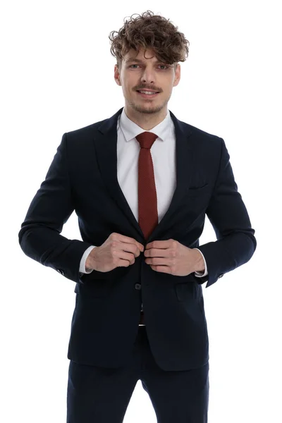Empresário Feliz Consertando Seu Casaco Sorrindo Enquanto Vestindo Terno Fundo — Fotografia de Stock