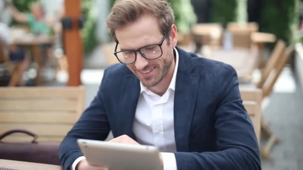 优雅而性感的商人在平板电脑上写了一封邮件 坐在桌旁 戴着眼镜 面带微笑 — 图库视频影像