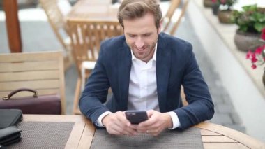 Sarışın, zeki, sıradan bir iş adamı masada oturuyor ve telefonuna mesaj atıyor.
