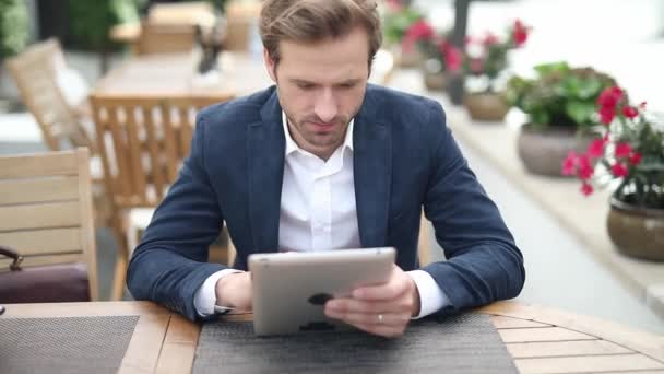 Elegante Homem Negócios Bonito Mensagens Seu Tablet Sentado Uma Mesa — Vídeo de Stock