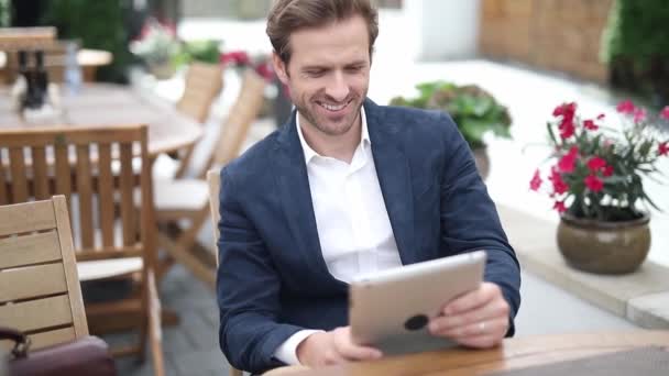 Hombre Negocios Sexy Rubio Sentado Una Terraza Leyendo Tableta Sonriendo — Vídeos de Stock