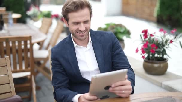 Blond Attractive Businessman Smiling Texting His Tablet Pointing Forward Sitting — Stock Video