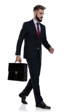Yan manzara genç işadamı bavulu tutuyor ve beyaz arka planda tek başına yürüyor.