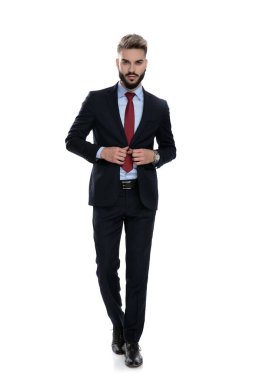 Takım elbiseli seksi genç adam beyaz arka planda tek başına yürüyor.