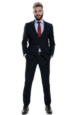 Genç ve seksi iş adamı ceplerinde el ele tutuşuyor, beyaz arka planda yalnız duruyor.