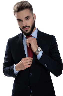 Seksi genç model kravatını düzeltiyor ve beyaz arka planda tek başına duruyor.