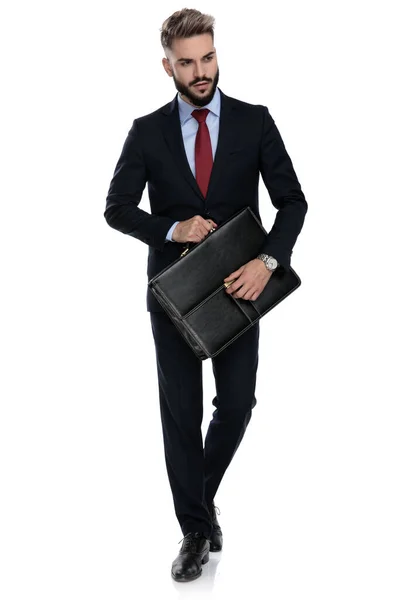 側を探しているセクシーな若いビジネスマンスーツケースを開き白い背景に隔離された歩行 — ストック写真