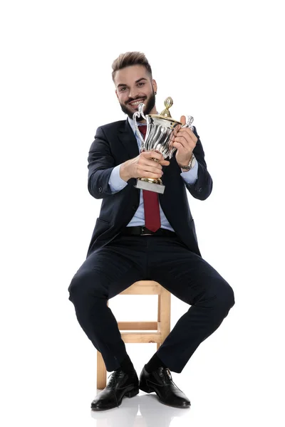 Orgulhoso Empresário Sorrindo Apresentando Troféu Sentado Isolado Fundo Branco — Fotografia de Stock