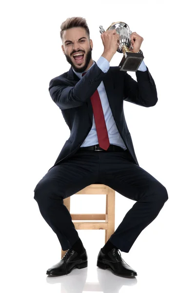 Animado Jovem Empresário Gritando Apresentando Troféu Sentado Isolado Fundo Branco — Fotografia de Stock